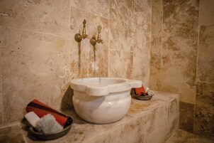 Un baño con lavamanos de mármol, inodoro y bidé. Hay toallas y un pequeño cuenco en la encimera.