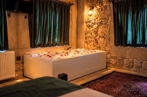 Un baño moderno con una bañera grande, paredes de piedra y cortinas verdes.