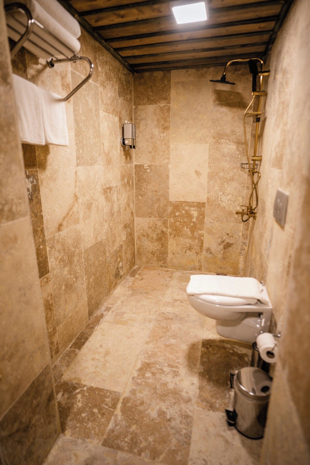 A small, enclosed bathroom with a shower, toilet, and a towel rack.