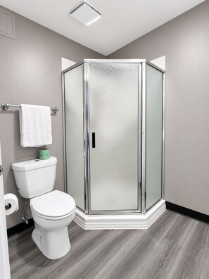 Une salle de bain moderne équipée de toilettes, d’une douche à parois de verre et d’un porte-serviettes.