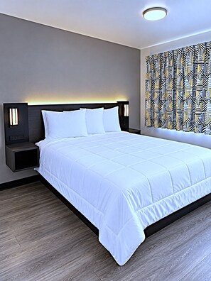 Une chambre d’hôtel avec un grand lit, des lampes de chevet, un rideau à motifs et un luminaire moderne au plafond.