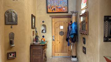 Ein Korridor mit einer Holztür, einem Teppich und verschiedenen Wanddekorationen, darunter ein Gemälde und gerahmte Gegenstände.