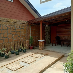 A covered patio area with stone walls, potted plants, and a seating area. - Block 23 Dogwood offers cleanliness, comfort, space and reliable security. (Bacolod City)