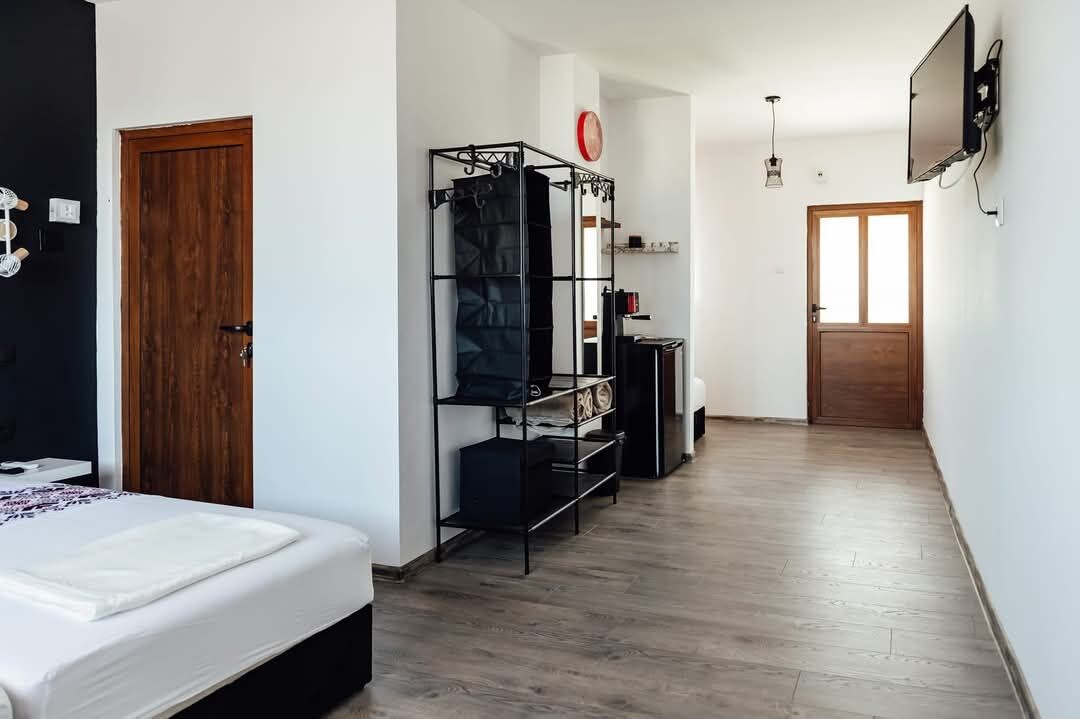 A hotel room with a bed, a wardrobe, a desk, and a television.