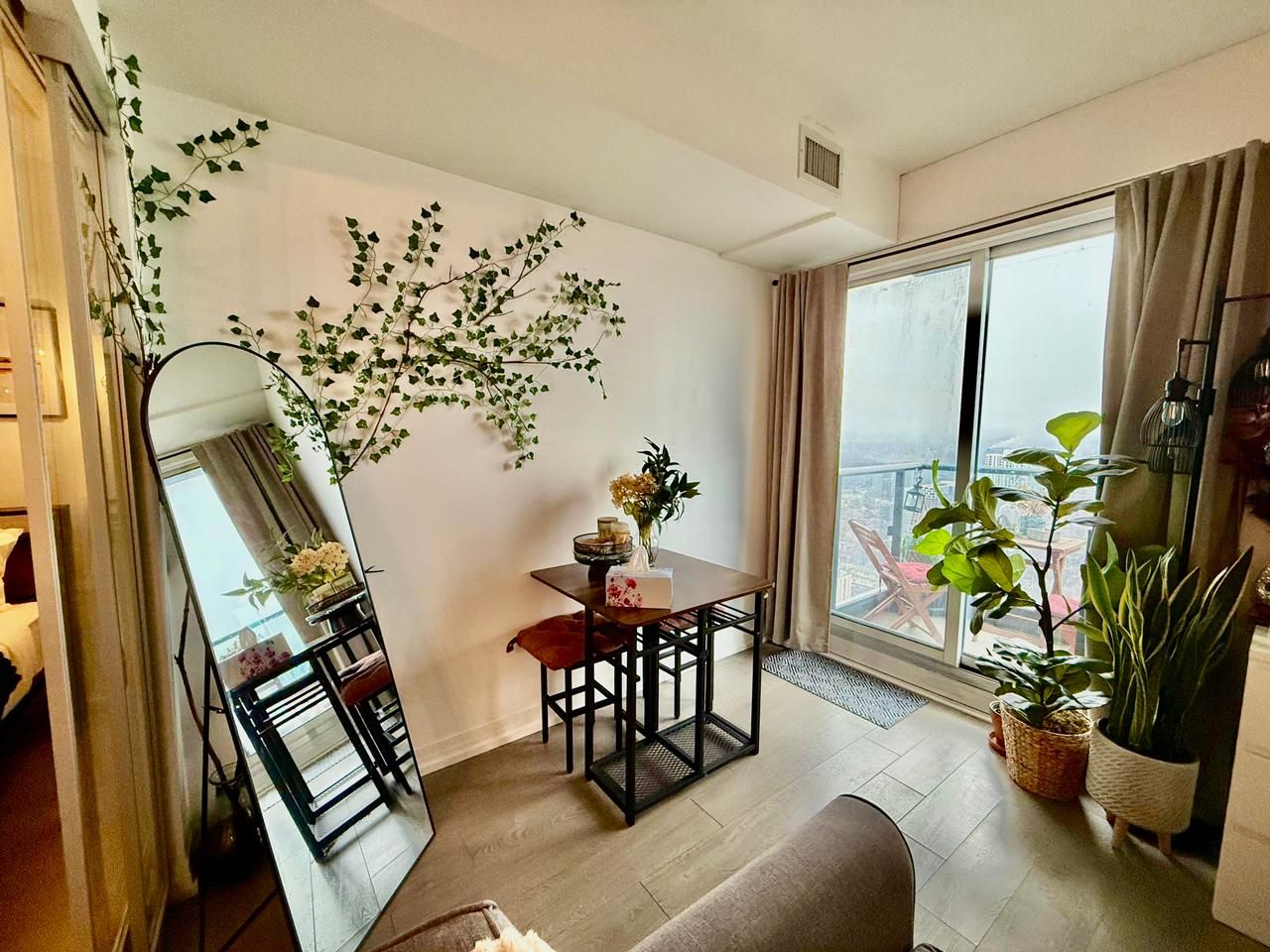 Uma sala de estar moderna com área de jantar, janelas amplas e plantas dentro de casa.