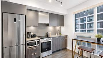 A modern kitchen with stainless steel appliances, a built-in oven, and a window overlooking a building.