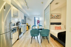 A compact hotel room with a kitchenette, a dining area, and a bed. - Dundas Suites - Heart of Downtown (Toronto)