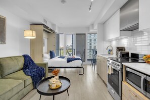 Un appartement moderne doté d’une kitchenette, d’un coin repas et d’une chambre avec une grande fenêtre.