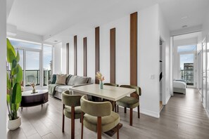 A modern living room with a dining area, large windows, and a city view. - Dundas Suites - Heart of Downtown (Toronto)