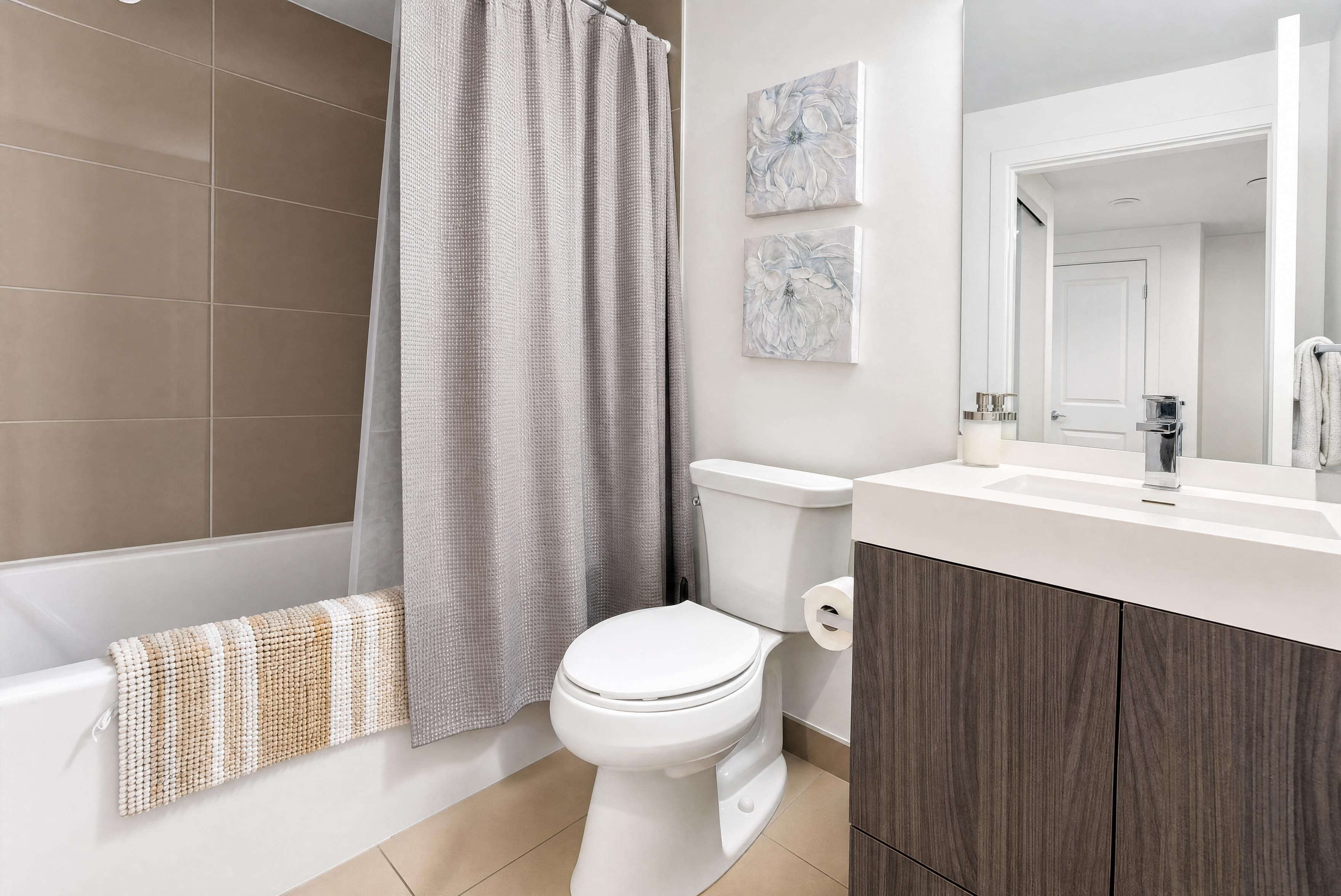 A modern bathroom with a bathtub, toilet, and a vanity with a mirror.