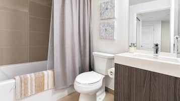 A modern bathroom with a bathtub, toilet, and a vanity with a mirror.