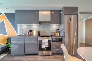 Une cuisine moderne avec des meubles gris, des appareils en acier inoxydable et un four encastré.