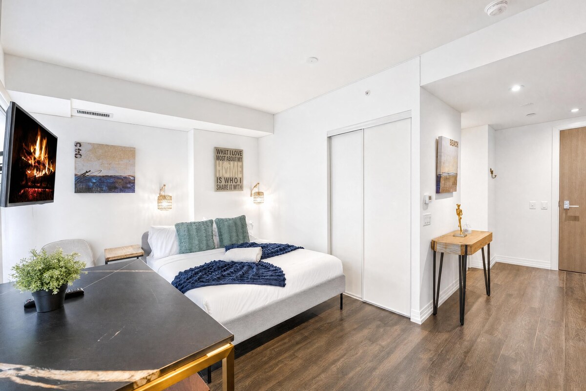 Een moderne slaapkamer met een bed, nachtkastjes, een televisie en kunstwerken aan de muur.