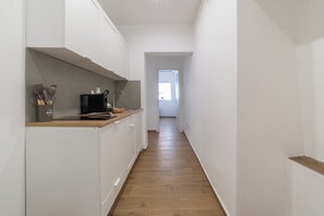 A narrow hallway with a kitchen area on the left, featuring cabinets, a microwave, and kitchen utensils. - New Listing (Palermo)