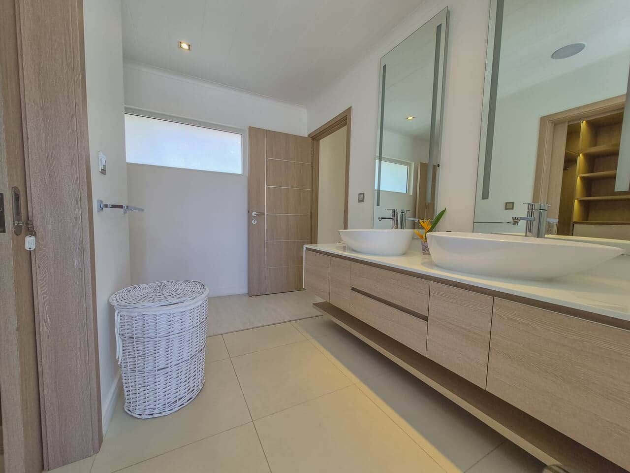 Uma casa de banho moderna com uma grande pia, espelho e armários de madeira.