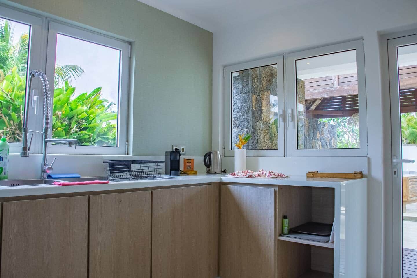 A kitchen with a sink, a coffee maker, and a window with a view of greenery.