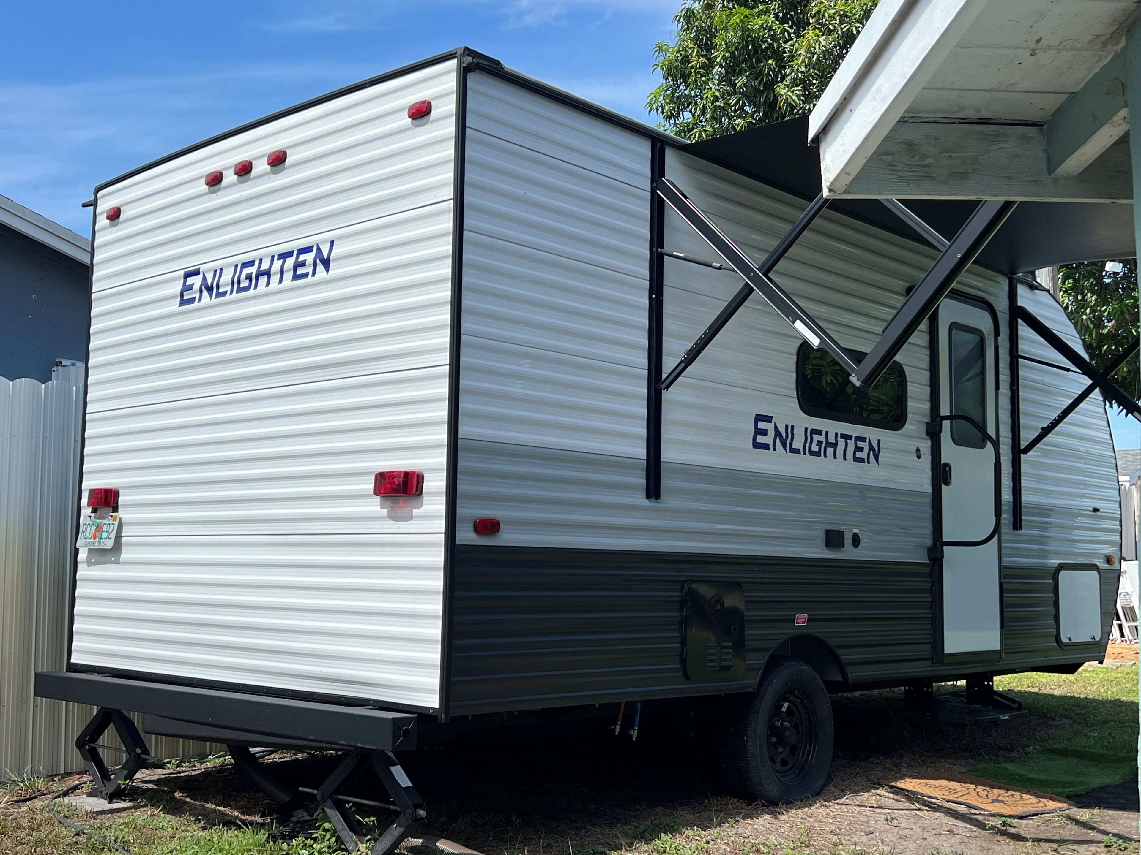 Een stilstaande camper met de merknaam 'ENLIGHTEN' op de zijkant, voorzien van een hellingbaan voor toegankelijkheid.
