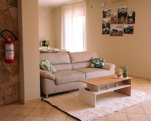 A living room with a beige sofa, a wooden coffee table, and a patterned rug. - New Listing (Carruba)