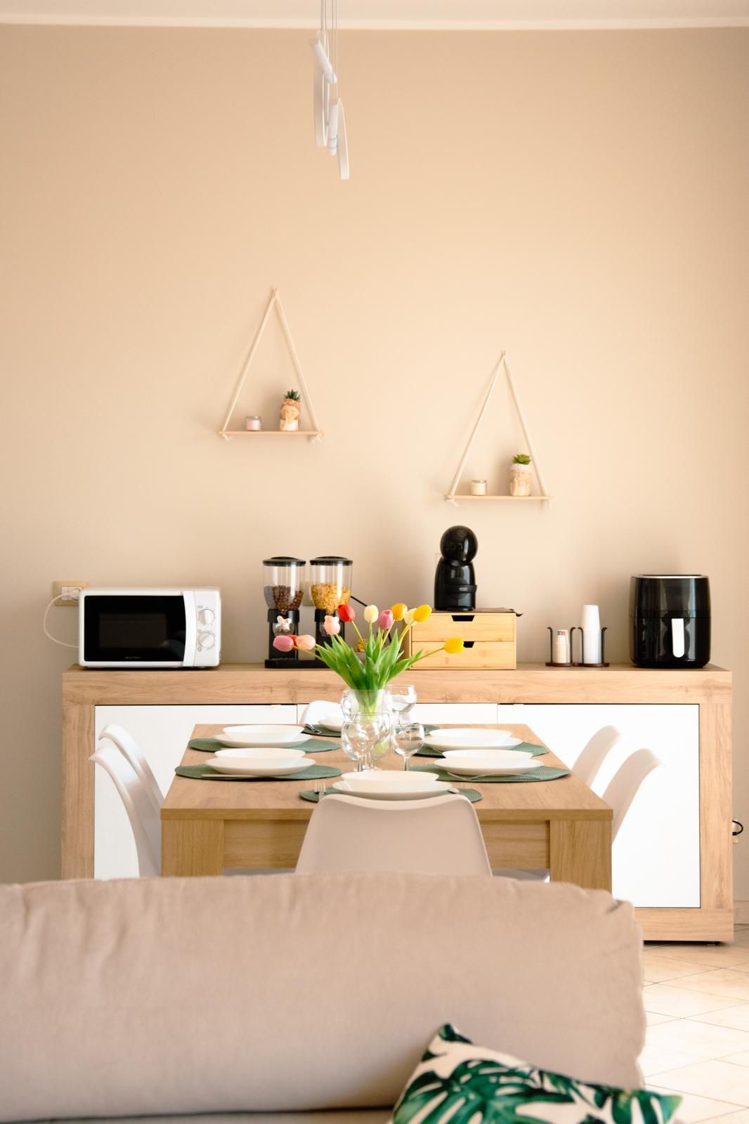 Uma cozinha moderna com micro-ondas, cafeteira e uma pequena estante com objetos decorativos.