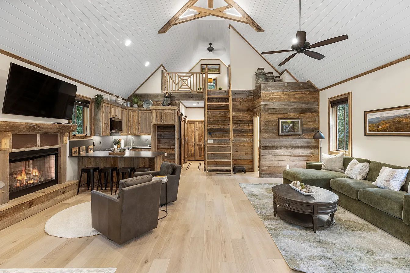 A spacious living area with a fireplace, a television, a dining area, and a loft space with a ladder.