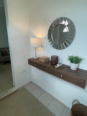 Eine wandmontierte Konsole mit Spiegel, Lampe und Dekorationselementen.