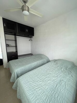 Ein Schlafzimmer mit zwei Betten, einem Deckenventilator und einem Kleiderschrank.