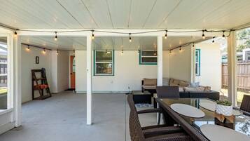 A covered patio area with wicker furniture, string lights, and a view of the backyard.