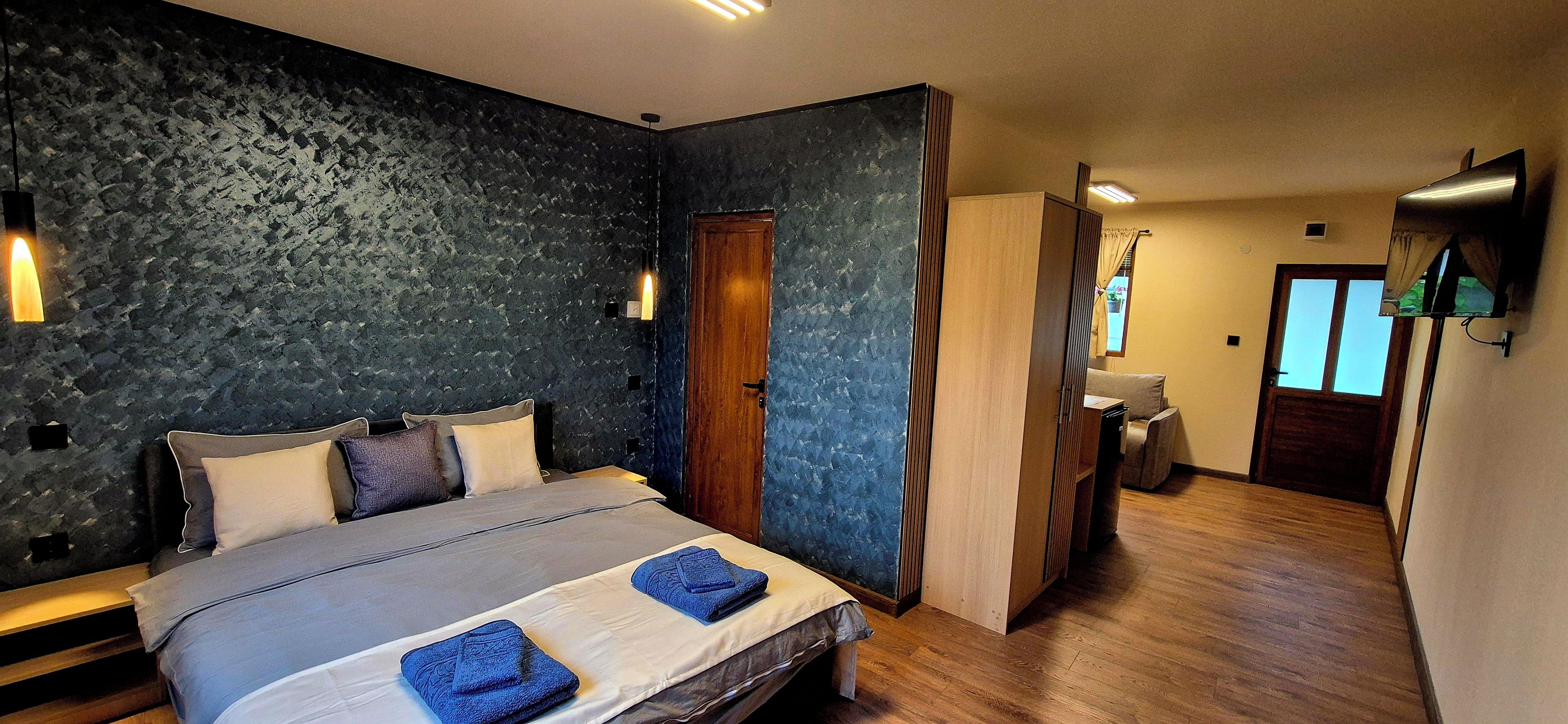 Ein Schlafzimmer mit einem Bett, Nachttischlampen, einer Holztür und Blick auf ein Badezimmer.