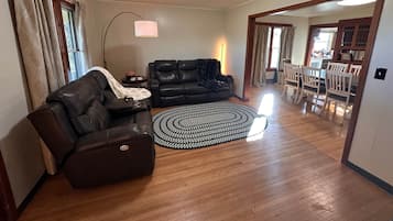Un salon avec un canapé en cuir, un tapis rond et un coin repas comprenant des chaises et une table.