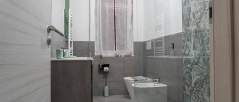 A bathroom with a toilet, sink, and shower area.