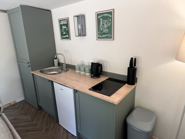 A compact kitchen with a sink, a coffee maker, and a trash bin. - A cozy cabin getaway featuring a relaxing hot tub and friendly goats. (Leominster)