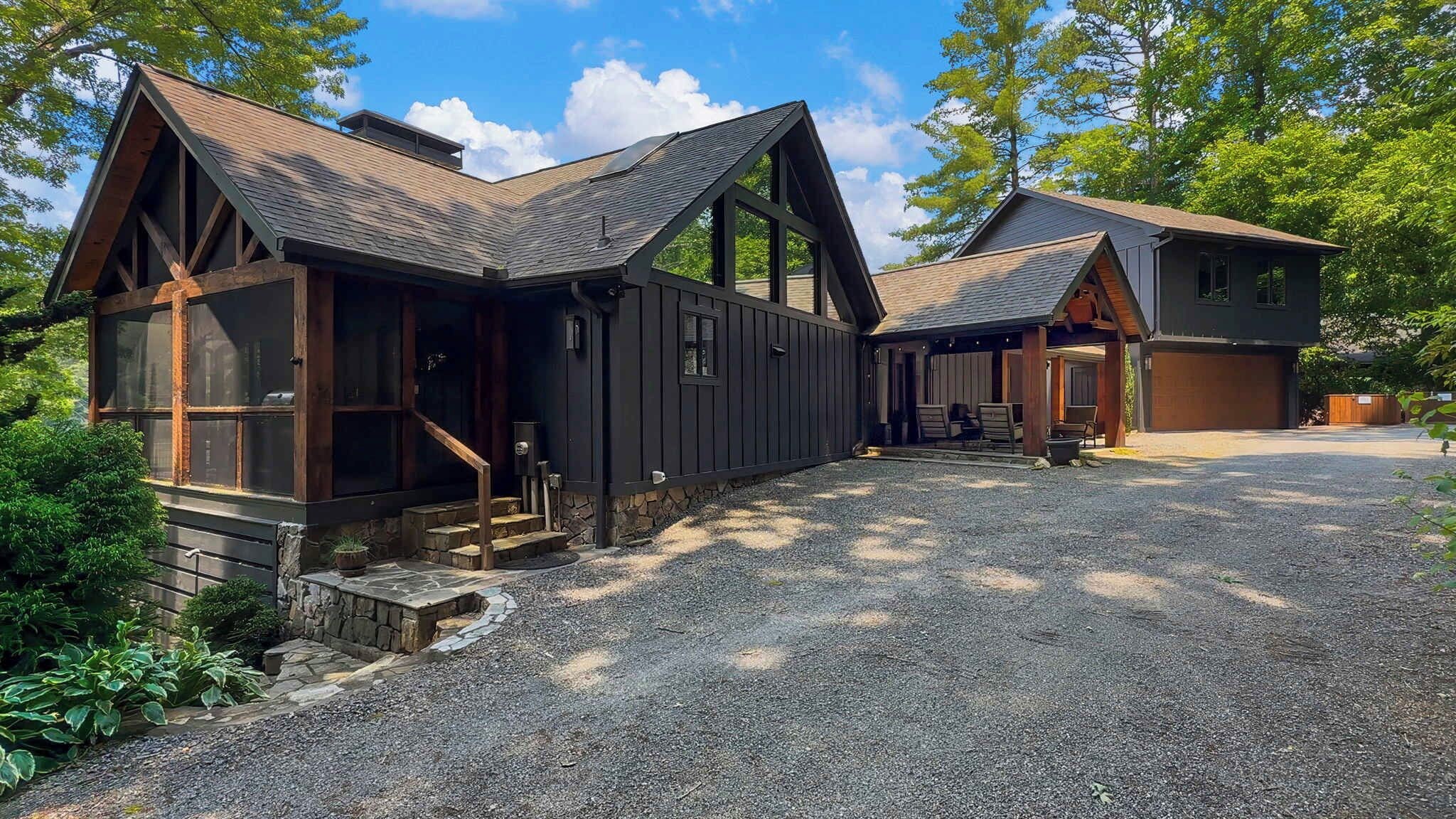 A two-story building with a stone foundation, large windows, and a gravel driveway.
