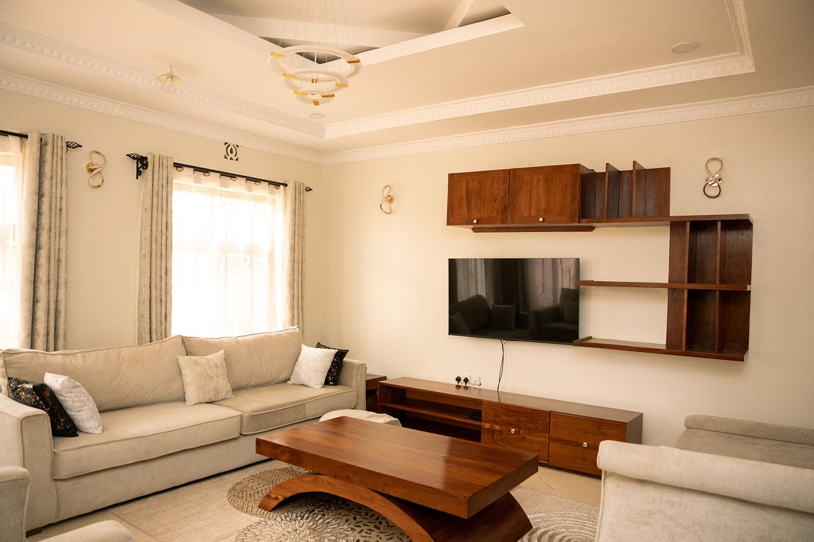 A living room with a sofa, coffee table, TV, and wooden shelving.