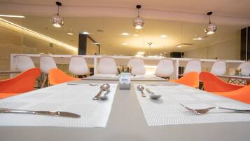 Uma sala de conferências com uma mesa comprida, cadeiras brancas e uma caixa rotulada 'kiora' no centro.