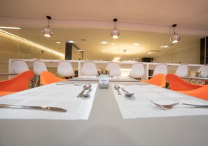 Uma sala de conferências com uma mesa comprida, cadeiras brancas e uma caixa rotulada 'kiora' no centro.