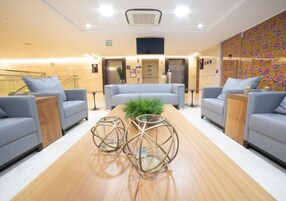 Un área de espera moderna con sofás, una mesa de madera y jarrones decorativos.