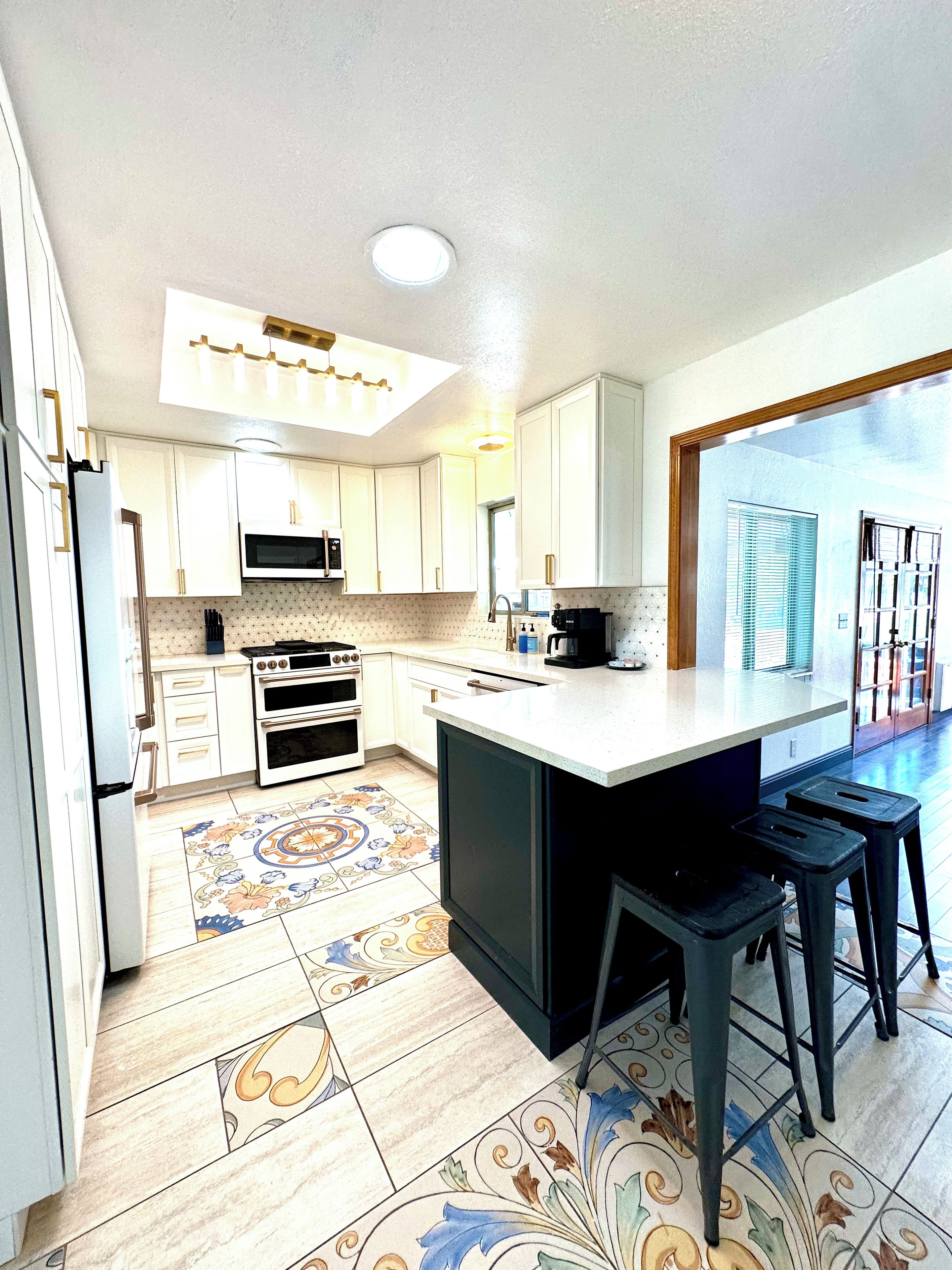 A modern kitchen with white cabinets, a central island, and a patterned floor.