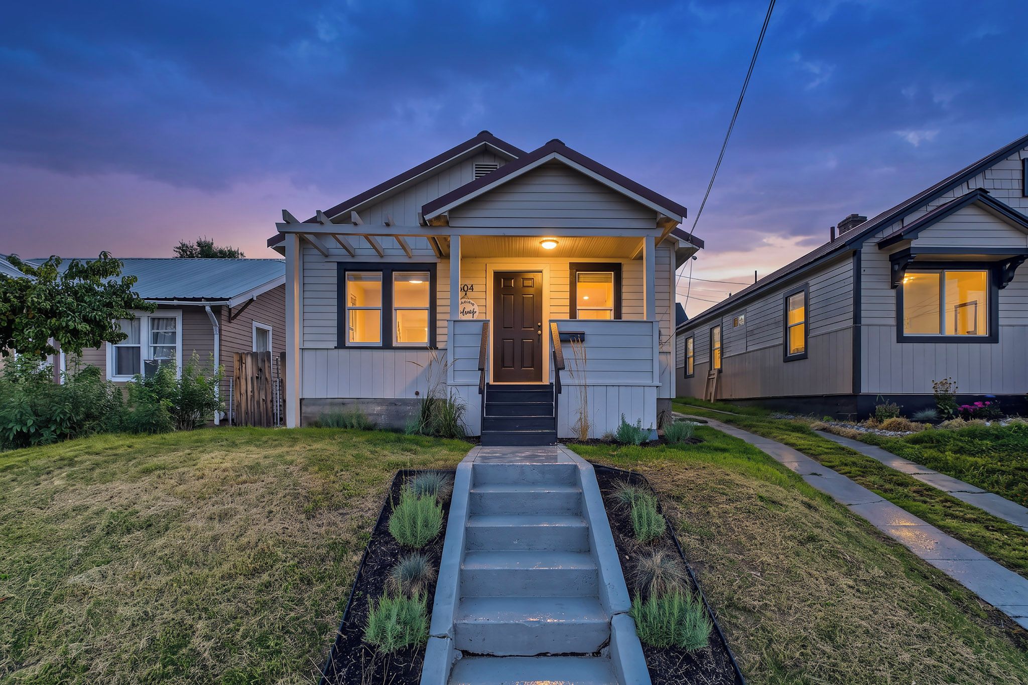 A residential house with a front porch, a staircase leading to the entrance, and a well-maintained lawn.