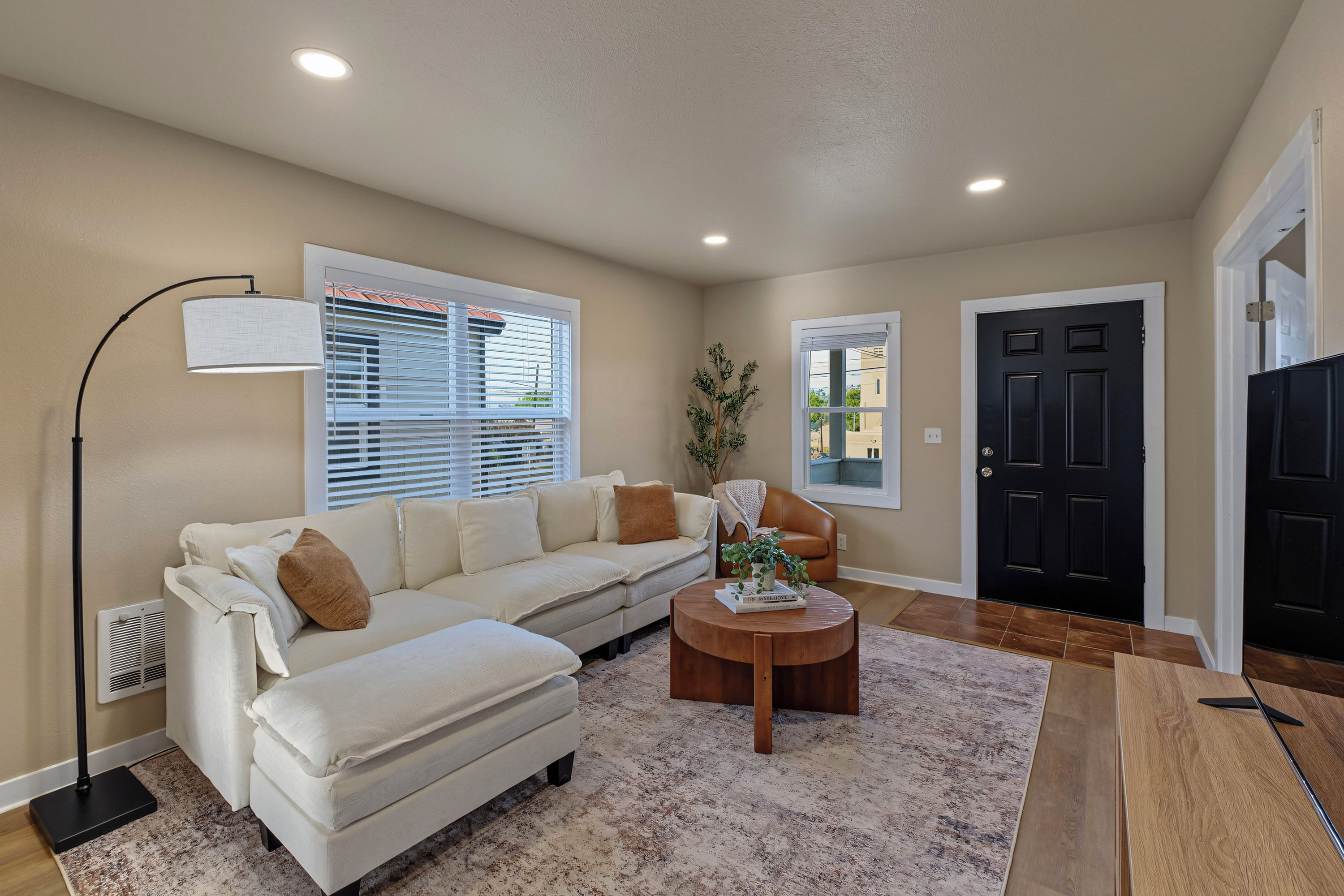 A living room with a sofa, a coffee table, a floor lamp, and a door.