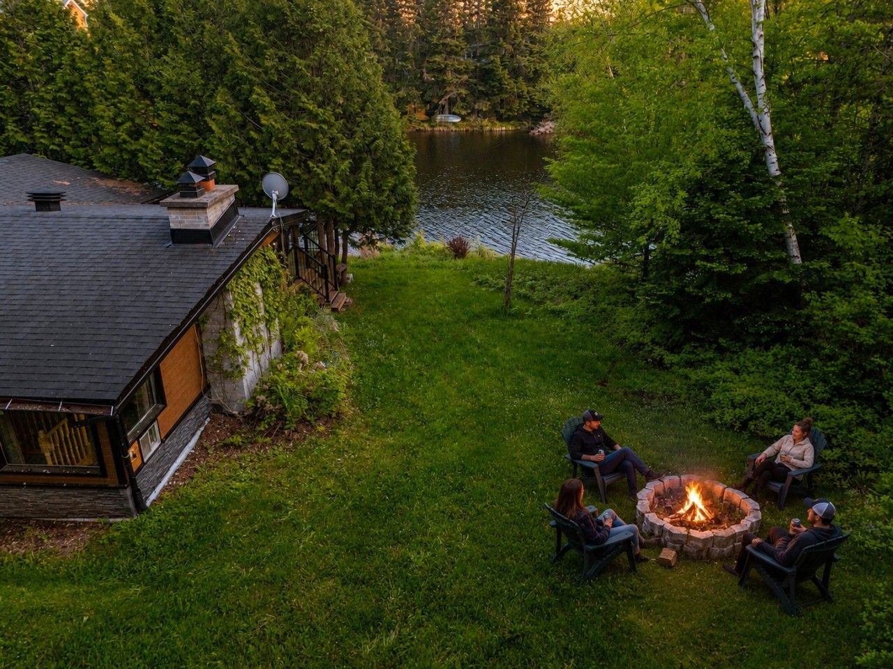 A lakeside cabin with a fire pit and outdoor seating.