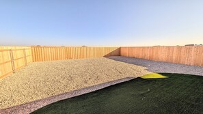 A rooftop terrace with a wooden fence, gravel flooring, and a section of artificial grass. - Modern 3BR Auburn St. Retreat (Lubbock)