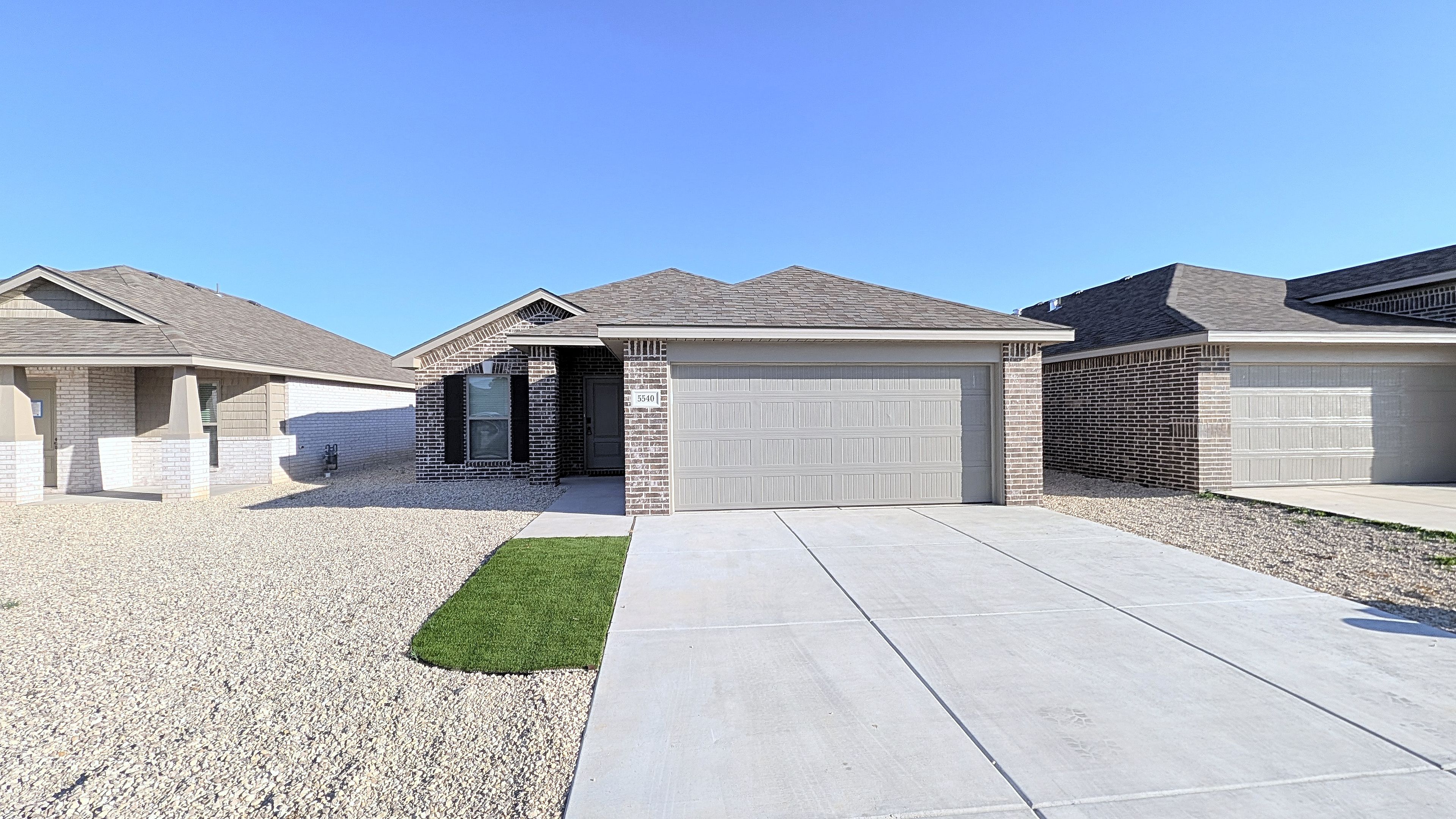A residential property with a driveway, a garage, and a well-maintained lawn.