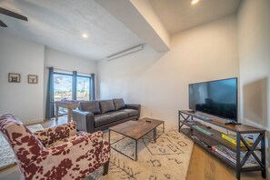 Ein modernes Wohnzimmer mit einer Couch, einem Couchtisch und einem Flachbildfernseher.