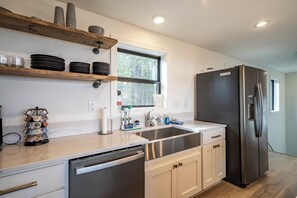 Eine moderne Küche mit integriertem Geschirrspüler, Edelstahlgeräten und einem Fenster, das für natürliches Licht sorgt.