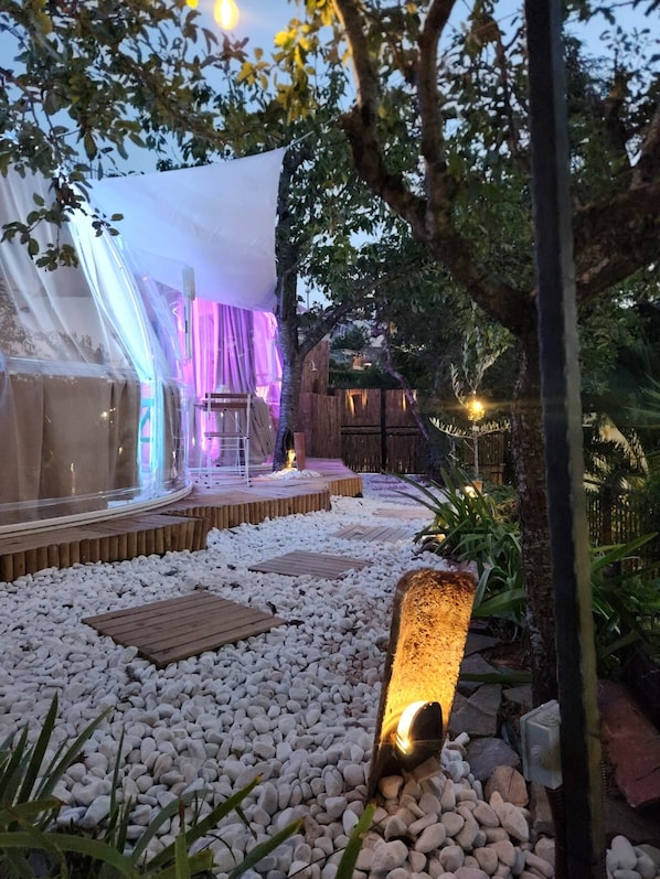Un espacio al aire libre con escenario, asientos e iluminación decorativa.