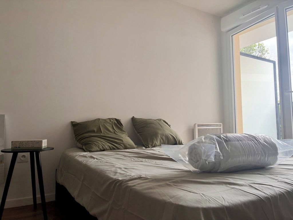 Une chambre à coucher avec un lit, des oreillers, une petite table et une fenêtre.