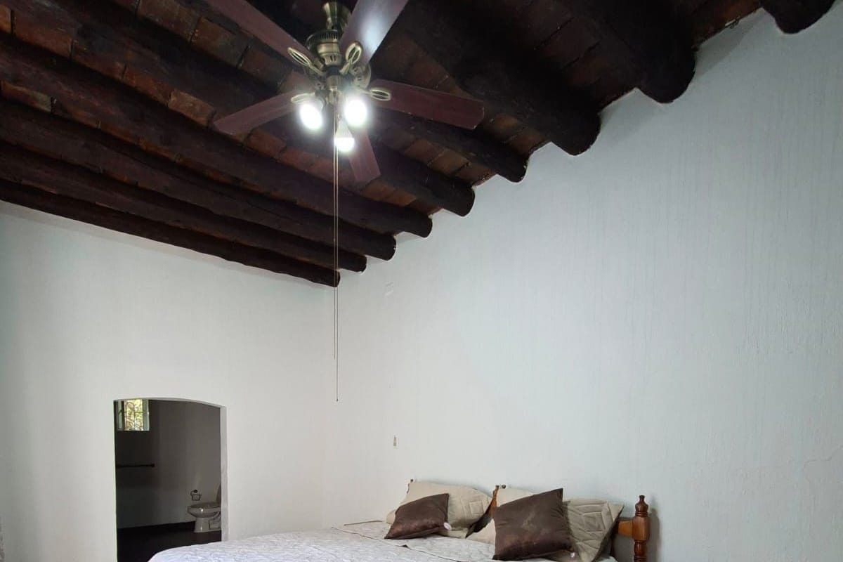 A bedroom with a bed, wooden headboard, a nightstand, and a ceiling fan.