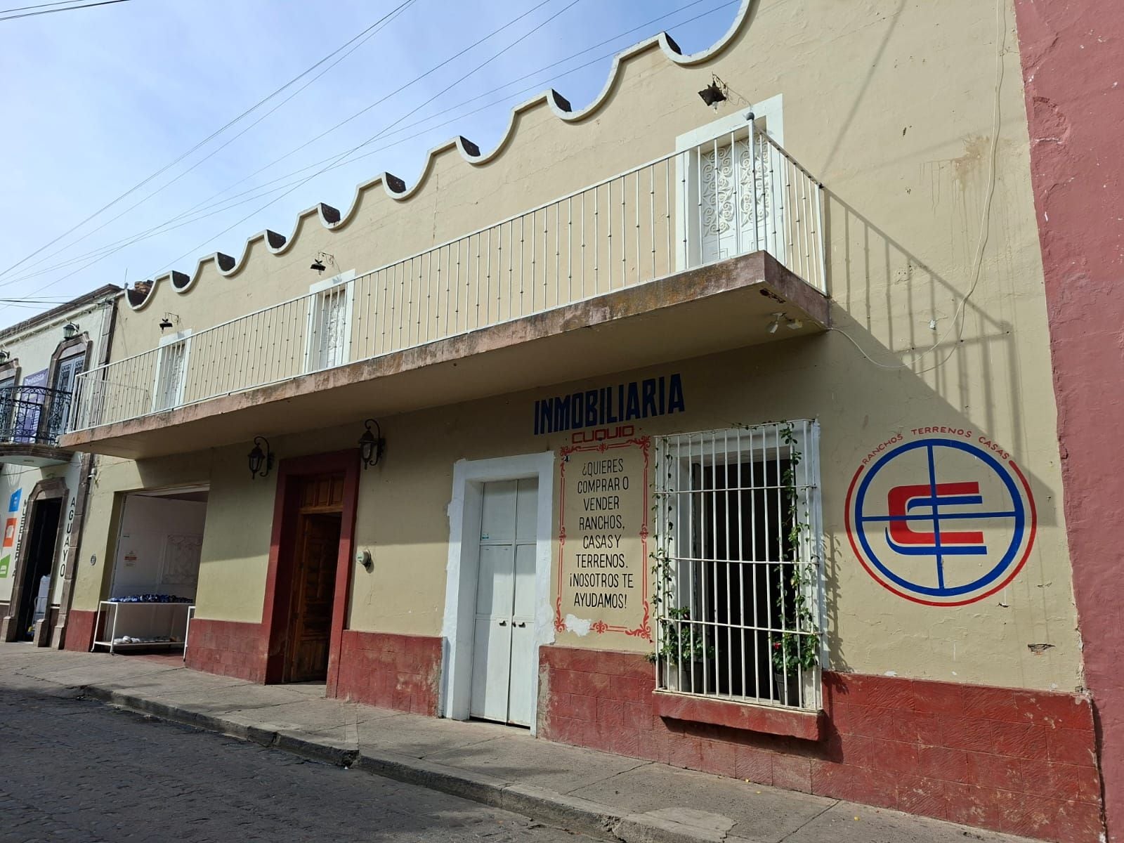 A two-story building with a sign that reads 'INMOBILIARIA' and a logo with a stylized 'E'.