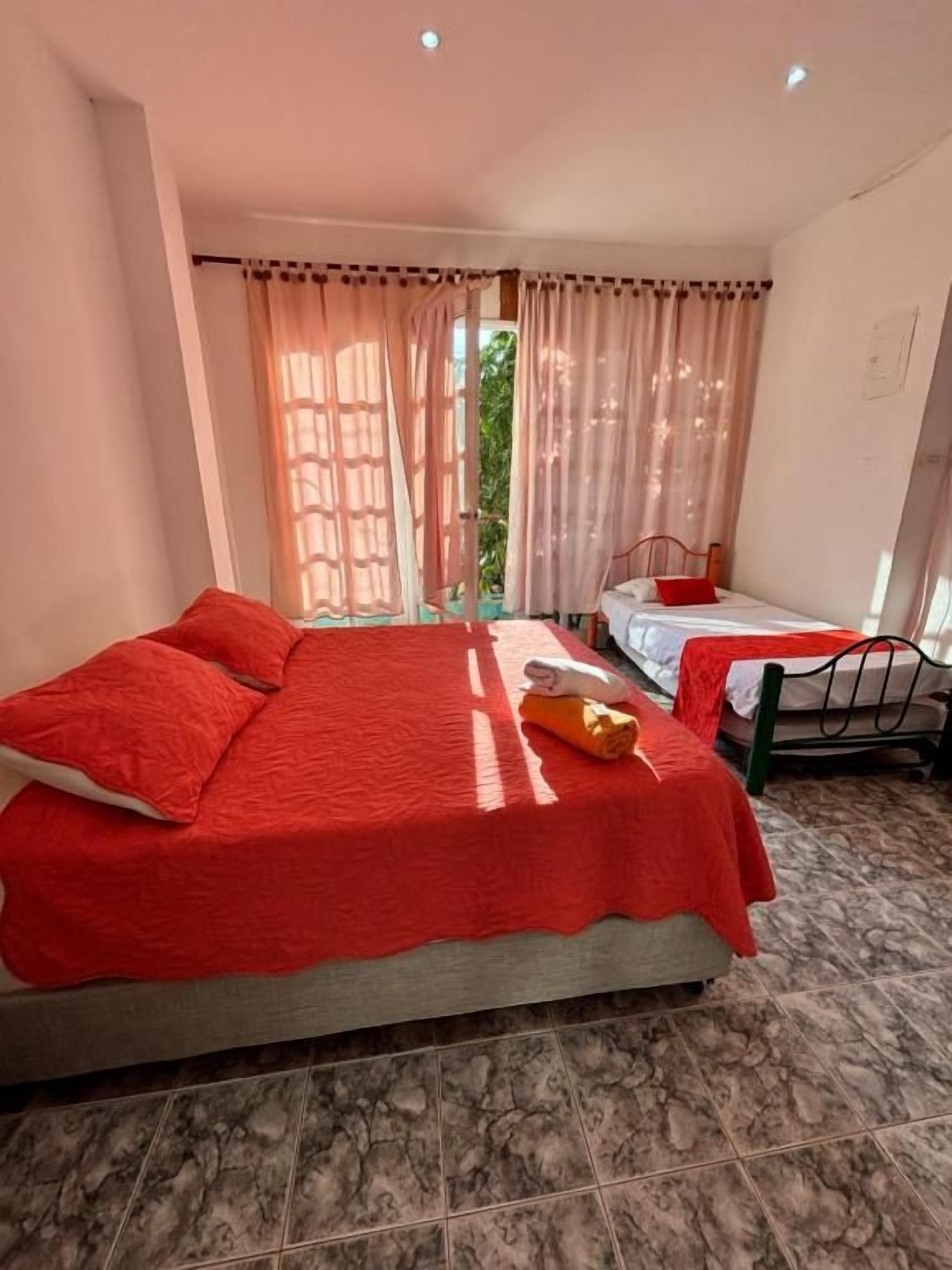 A bedroom with a bed, a bedside table, and a window with curtains.