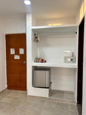 A room with a wooden door, a white shelf with a radio, and a small cabinet.
